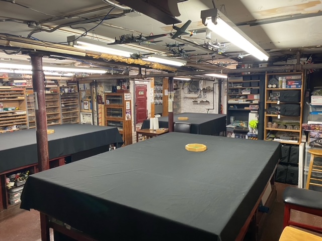 The back room at Metropolitan Wargamers, featuring sand tables and walls of lined with miniatures and games.