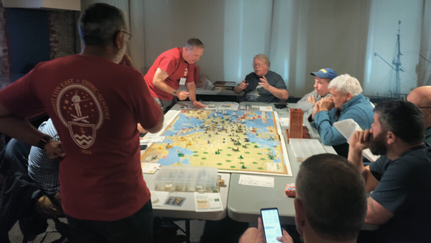 Designer Mark McLaughlin (top, seated) showing off his personal copy of his "The Napoleonic Wars" game at SDHistCon East 2024.