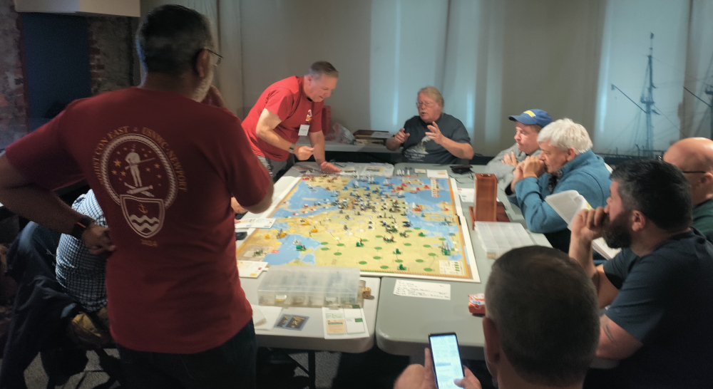 Designer Mark McLaughlin (top, seated) showing off his personal copy of his "The Napoleonic Wars" game at SDHistCon East 2024.